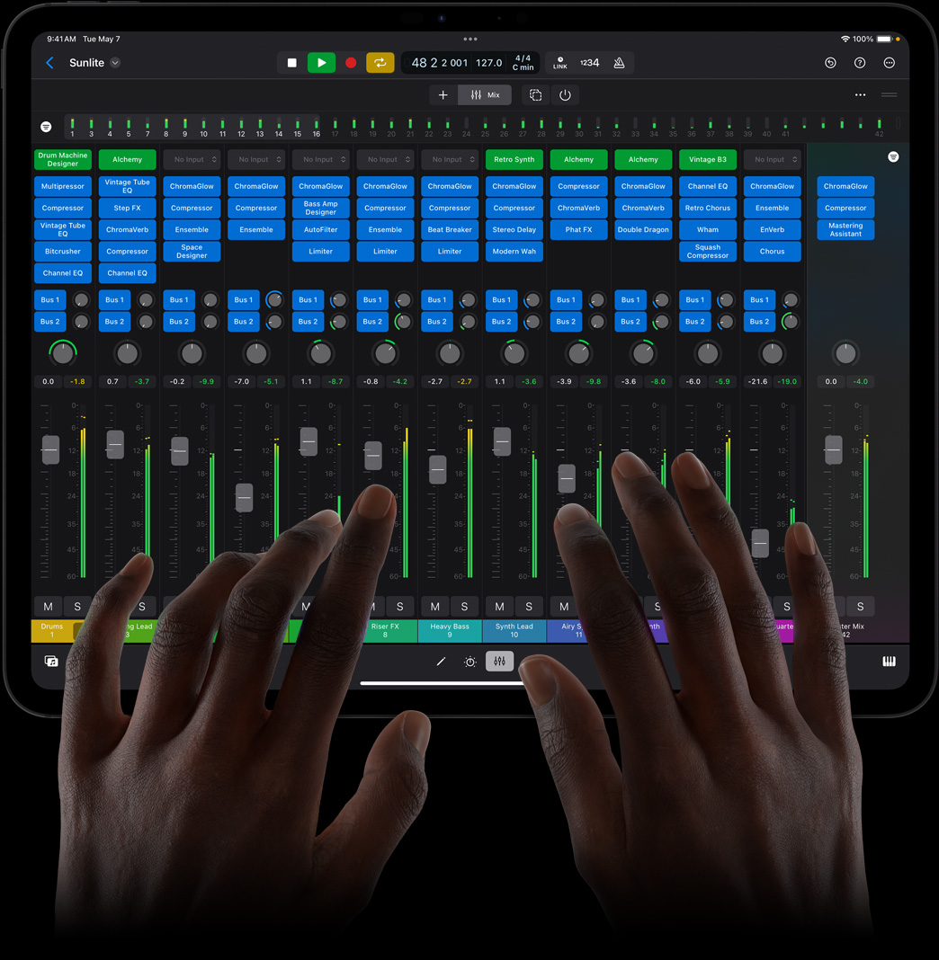 一双手点触 iPad Pro 屏幕，正在使用 iPad 版 Logic Pro 的全功能混音控制台。